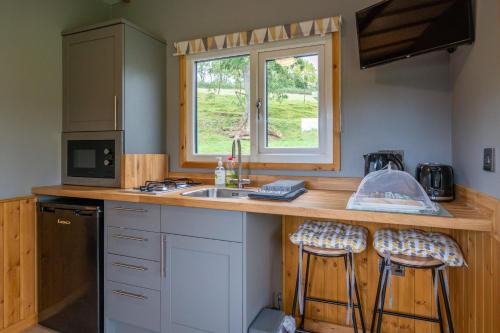 a kitchen with a sink and a counter with stools at The Elm Shepod - Smardale Mill in Smardale