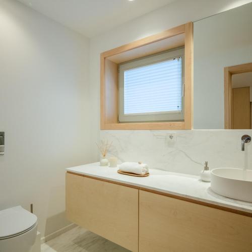 a bathroom with a sink and a toilet and a window at 70's wood house in Maia