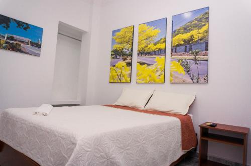 Zimmer mit einem Bett und vier Gemälden an der Wand in der Unterkunft Hotel Casa Martina Valledupar in Valledupar