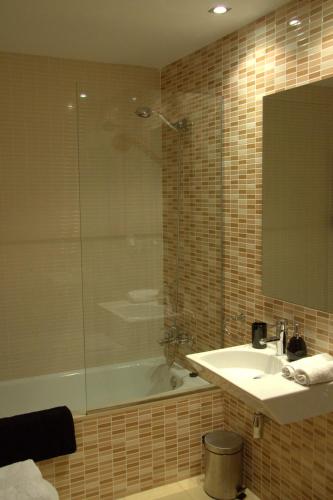a bathroom with a sink and a tub and a mirror at Las Coles Apartasuites in Xàtiva
