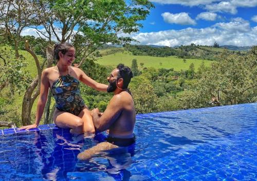 um homem e uma mulher sentados numa piscina em Chalé Arara super Luxo em Cunha