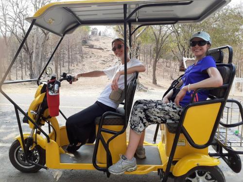 two women riding on a golf cart at Toon Guesthouse in Sukhothai