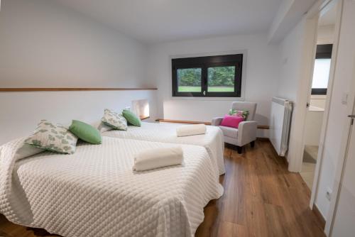 2 camas en una habitación blanca con ventana en Finca Bacelo Ribeira Sacra, en Sober