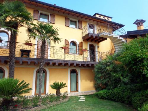 a yellow house with a balcony and palm trees at Albergo Le Piante in Manerba del Garda