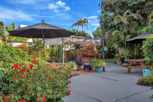 a patio with an umbrella and some plants and flowers at Oasis Hotel in Fort Lauderdale