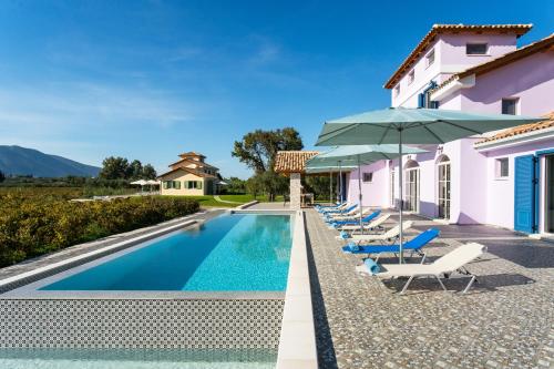 uma piscina com cadeiras e guarda-sóis ao lado de uma casa em Aneli Luxury Villas - Villa Alexandra em Áyios Kírikos