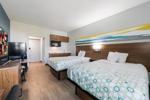 a hotel room with two beds and a flat screen tv at HomeTowne Studios by Red Roof Newport News - Hampton West in Newport News