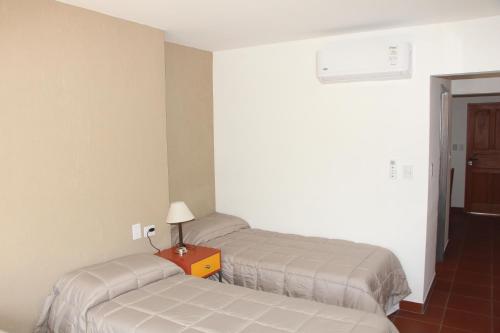 Habitación con 2 camas y mesa con lámpara. en Departamentos Ibazeta en Salta