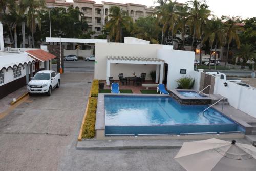 a swimming pool with a boat parked in front of it at Mar Sol Bungalows & Hotel in Mazatlán