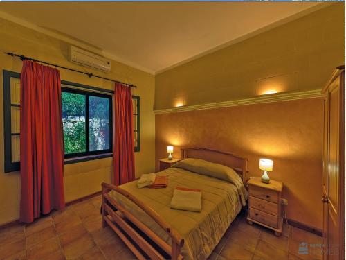 Schlafzimmer mit einem Bett und einem Fenster mit roten Vorhängen in der Unterkunft Casetta Menzja Semi Detached Bungalow in Sannat
