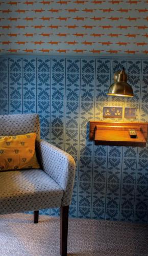 a room with a chair and a table with a lamp at The Bay Horse, Masham in Masham