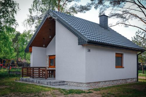 een klein wit huis met een zwart dak bij Domek letniskowy SZWED-POL in Kujan