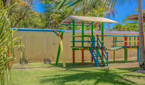 um parque infantil com equipamento colorido em frente a uma piscina em Arraial Bangalô Praia Hotel em Arraial d'Ajuda