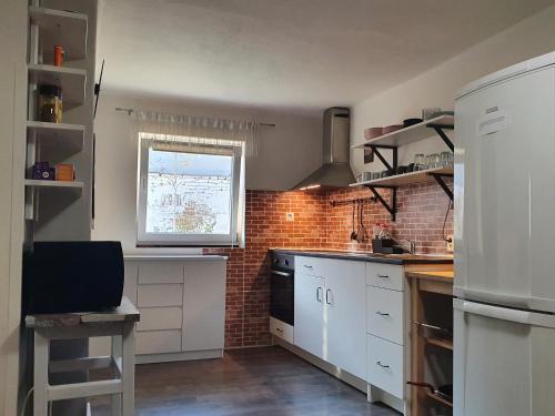 a kitchen with white cabinets and a brick wall at Ubytování u Ještěrky in Jaroslavice