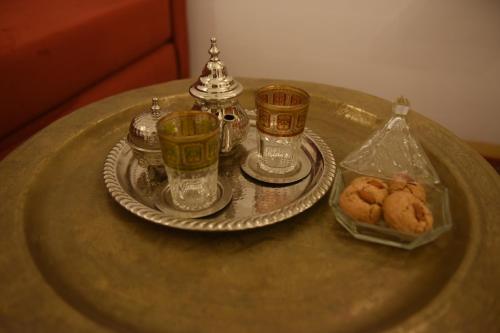 a table with two cups and a plate with cookies on it at Riad Nouceiba Marrakech in Marrakech