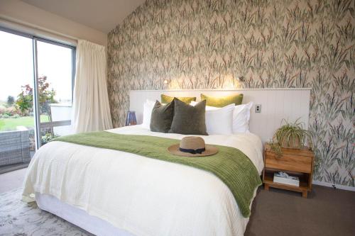a bedroom with a large bed with a hat on it at Dunluce Boutique B&B in Te Anau