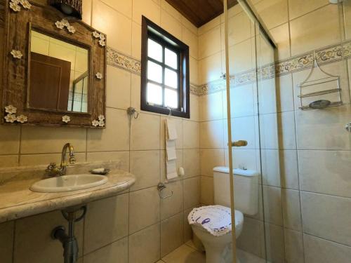 uma casa de banho com um WC, um lavatório e um espelho. em Vista espetacular, churrasqueira gourmet e piscina aquecida em Ilhabela
