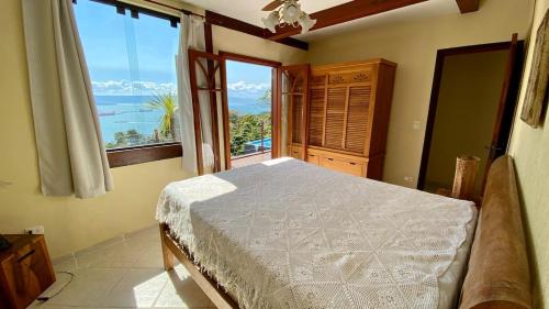 um quarto com uma cama e vista para o oceano em Vista espetacular, churrasqueira gourmet e piscina aquecida em Ilhabela