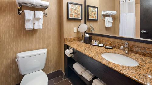 a bathroom with a sink and a toilet and a mirror at Best Western Premier Freeport Inn Calgary Airport in Calgary