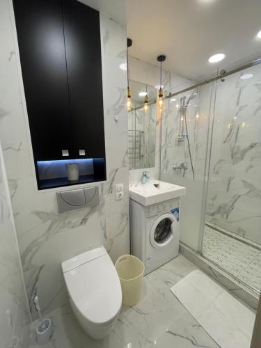 a bathroom with a toilet and a tv on the wall at Krivenko 49 Str by Slissenko Inn in Pavlodar