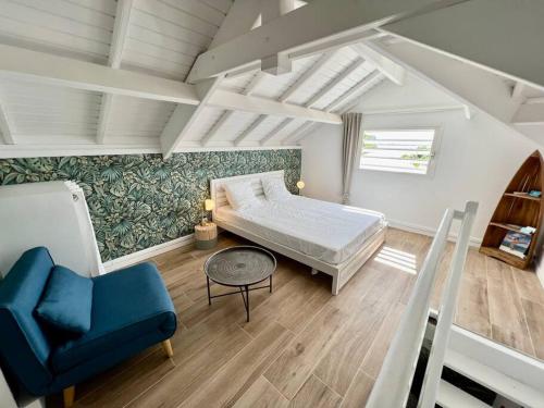 een slaapkamer met een bed en een blauwe stoel bij Duplex JUNGLE BLEUE Terrasse vue mer incroyable in Marigot