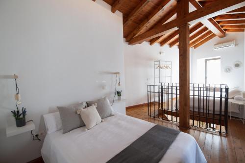 una camera con letto bianco e soffitto in legno di El Postigo a Trujillo