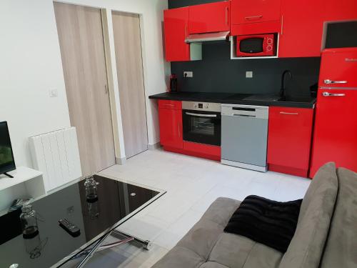 - une cuisine avec des placards rouges et un canapé dans la chambre dans l'établissement villa pura vida, à Saint-Martin-Vésubie