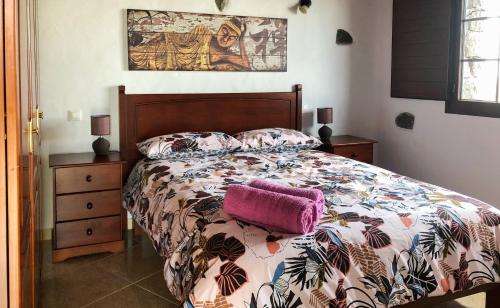 Sun, Relax & Lava, Free wifi 600mb, BBQ في تيناجون: غرفة نوم مع سرير مع وسادة أرجوانية عليه