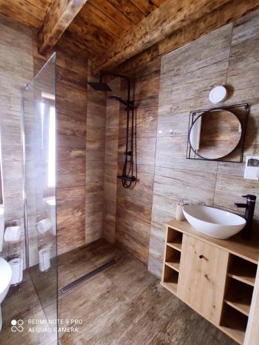 a bathroom with a shower and a sink and a mirror at Domki Wilcze Siedlisko - Bieszczady in Hużele