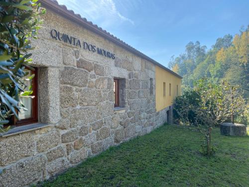 a stone building with a sign on the side of it at Quinta dos Mouras in Celorico de Basto