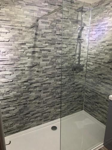a bathroom with a glass shower with a stone wall at Riverside Chalet Borve Isle of Lewis in Borve