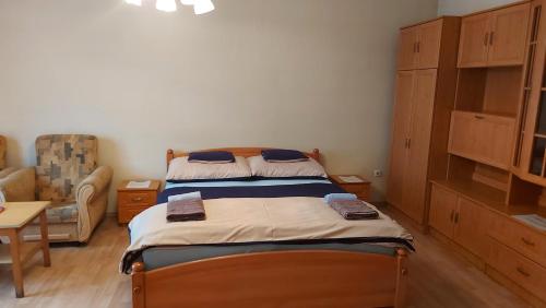 a small bedroom with a bed and a chair at Peró Apartman in Debrecen