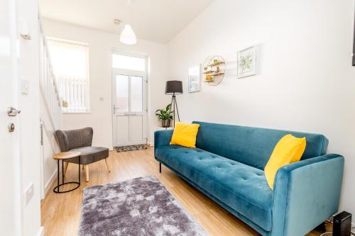 een blauwe bank in een woonkamer met gele kussens bij 5-10 Off Weekly-Monthly Stays for Groups, Family Relocation, Contractors or Corporate bookings in Northampton