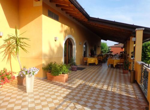 a building with a patio with tables and potted plants at Albergo Le Piante in Manerba del Garda