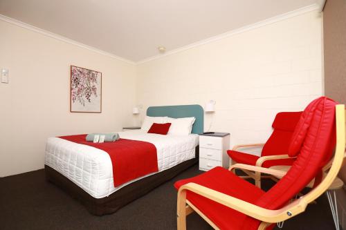 a bedroom with a bed and a chair at Albatross Motor Inn in Lakes Entrance