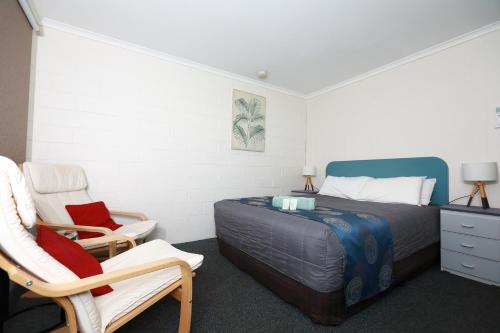 a bedroom with a bed and two chairs at Albatross Motor Inn in Lakes Entrance