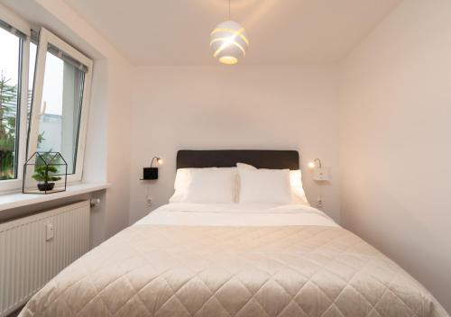biała sypialnia z łóżkiem i oknem w obiekcie Stadium & garage w Bratysławie