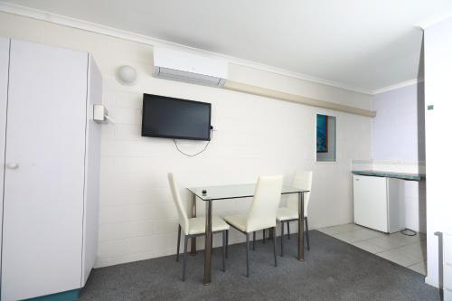 a dining room with a table and chairs and a tv at Albatross Motor Inn in Lakes Entrance