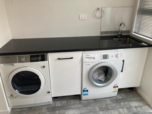 a kitchen with two washing machines and a sink at Trendy Bungalow in the Heart of Rotorua in Rotorua