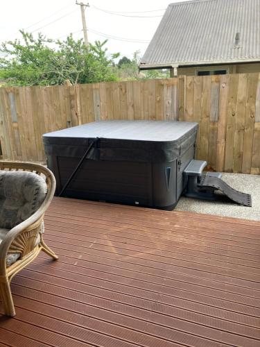 a hot tub sitting on a deck next to a fence at Trendy Bungalow in the Heart of Rotorua in Rotorua