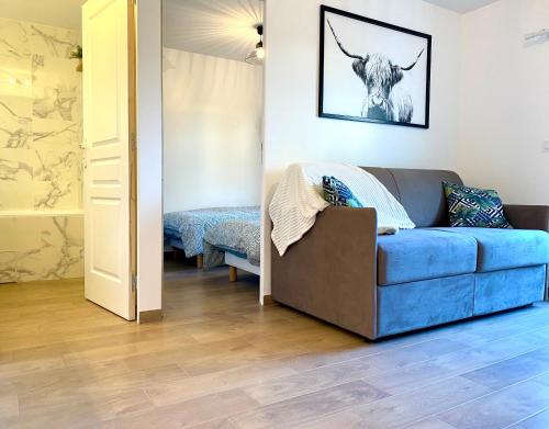 a living room with a blue couch and a cow on the wall at Perle Marine au pied de la plage in Cabourg