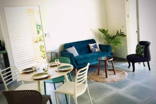 a living room with a blue couch and a table and chairs at Cottage « the papaya tree » in Temae