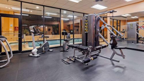 a gym with several tread machines and a swimming pool at Best Western Plus Hotel & Conference Center in Baltimore