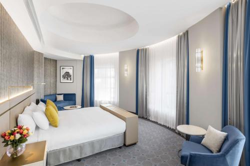 a hotel room with a white bed and blue chairs at Paradox Sydney in Sydney