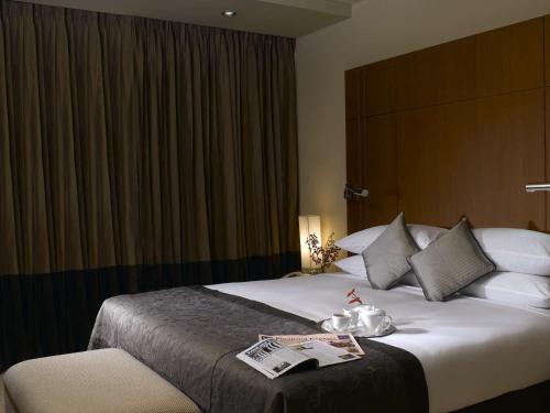 a hotel room with a bed with a newspaper on it at Radisson Blu Dhaka Water Garden in Dhaka