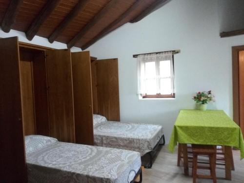 Casa do Pastor في لوسا: غرفة بسريرين وطاولة ونافذة