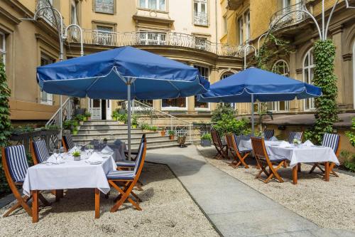 a group of tables with blue umbrellas in front of a building at Radisson Blu Hotel Schwarzer Bock Wiesbaden in Wiesbaden