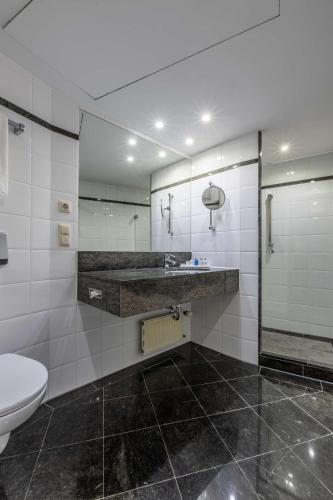 a bathroom with a toilet and a sink and mirror at Radisson Blu Hotel Schwarzer Bock Wiesbaden in Wiesbaden
