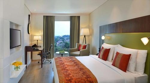 Country Inns & Suites By Radisson Manipal في مانيبال: غرفه فندقيه سرير كبير وتلفزيون