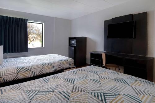 Habitación de hotel con 2 camas, escritorio y TV. en Motel 6-Merrillville, IN, en Merrillville